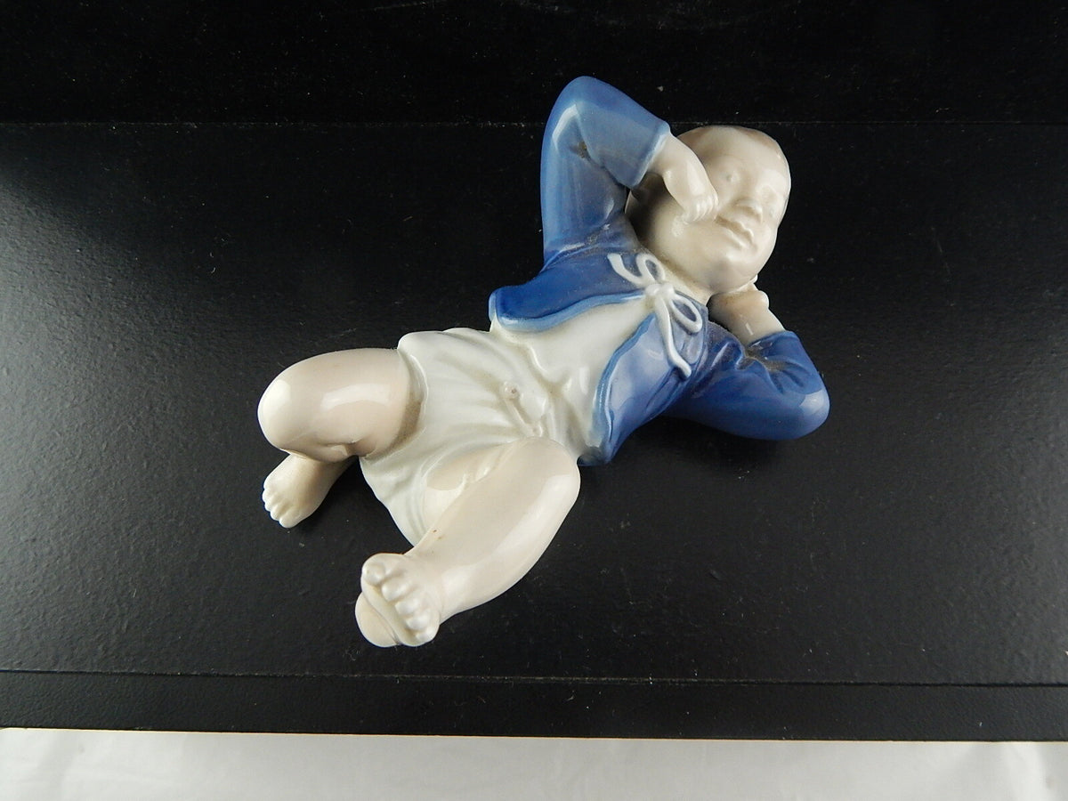 Royal Copenhagen Statuina in "Bambino Sdraiato" Cod 4669 porcellana dipinta a mano, 14 cm